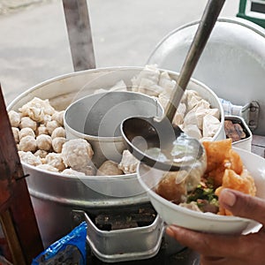 A Street Food Vendor Preparing a Bowl of Delicious Indonesian Authentic Bakwan Malang on a Pushcart