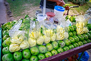 A street food vendor slices fresh green mango which sells on foo