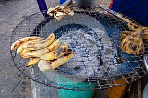 Street foods in Lagos Nigeria; roadside charcoal grill with roasted  yam, plantain and sweet potato