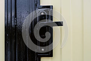 Street gate with corrugated sheet covering and black door knob and lock close-up