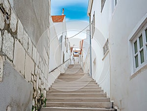 street going to the lighthouse bordered by houses with orange roofs, infinite street climbing to the sea