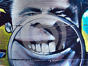 Street graffiti on the public wall caricature head of a man with magnifying glass and teeth. Novi sad Serbia 08.14.2010