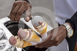 A street hawker scoops chocolate and cheese sorbetes into in small wafer cones. Traditional ice cream in the Philippines