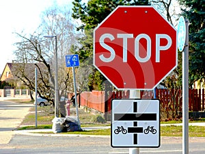 Street intersection with red STOP sign and bicycle route traffic sign