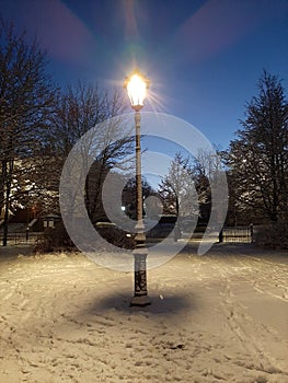 street lamp with bench in winter in the dark