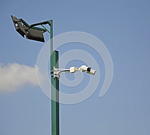street lamp with CCTV cameras on a metal pole against blue sky