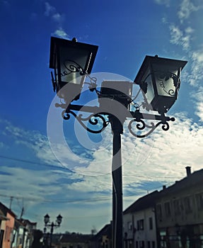 Street lamp, city and blue sky with clouds