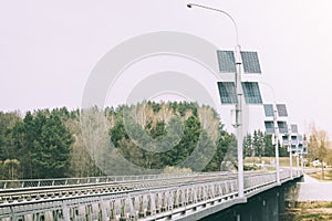 Street lamp poles powered by solar energy. Solar panels on electric pole for lighting on the road in the city on the bridge