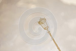 Street lamp. Reflection in a puddle against a cloudy sky in cloudy weather. Blurry image