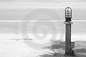 Street lamp on timber with ground wire beside walkway on the road.