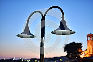 Street lamp with white light shining mysteriously in the sunset of a town photo