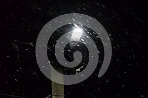Street lamp at winter night during snowfall
