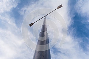 Street lamppost with two searchlights in the daytime against a background of blue sky with white clouds