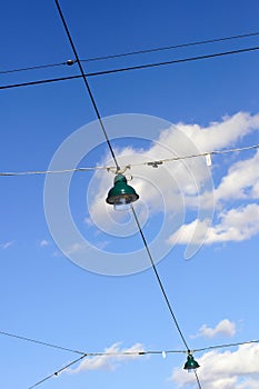 Street lamps on wires against cloudy blue sky