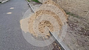 on the street lies a folded pile of sand or red clay. repair of the road of the
