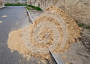 on the street lies a folded pile of sand or red clay. repair of the road of