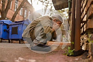 Street life, homeless man squating to wash face.