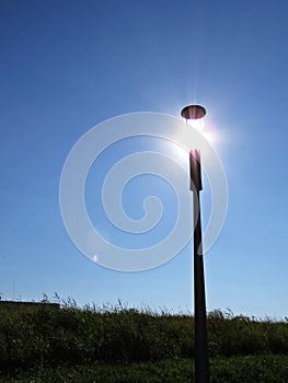 Street Light Lamp with Sun Shine Light on Blue Sky