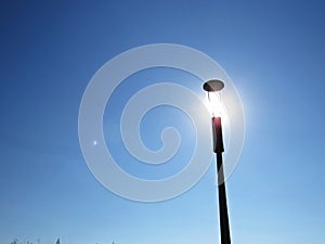 Street Light Lamp with Sun Shine Light on Blue Sky