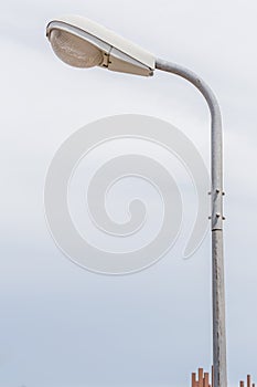 A street light pole with blurred nature scene of cloudy sky back