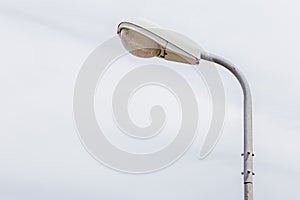 A street light pole with blurred nature scene of cloudy sky back