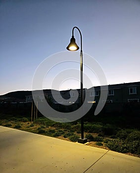 a street light on a walk way at dusk in a suburban area