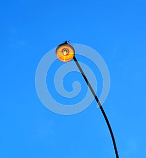 Street lighting lamp lit at dusk on a long pole