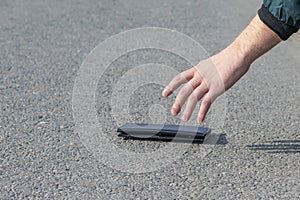 Street lighting. there is a wallet on the road on a sunny summer day. A human hand reaches out to him