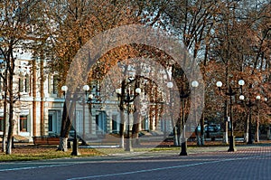 Street lights on an autumn evening. Historic building in the shade of the foliage of trees.