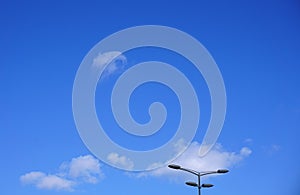 Street lights in daylight against a beautiful blue sky with white clouds