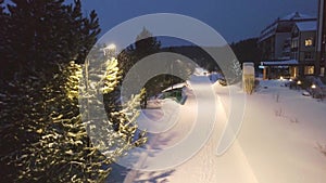 Street lights illuminate path with people walking in park in winter. Clip. Beautiful winter evening with people walking