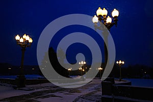 Street lights and road illuminated street lamps and snowing in winter at twilight.