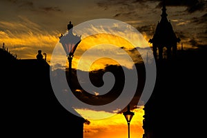 Street lights and silhouettes of historical buildings against an orange sky at twilight time in Oradea, Romania