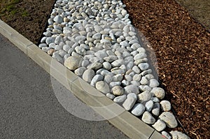 The street line is planted in a rectangular strip mulched by large white pebbles. clearer and more formal appearance than mulch ba