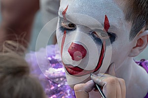 Street makeup. The image of a clown or mime. Costume for carnival or holiday halloween. Cosplay at a horror party. Artist`s hand