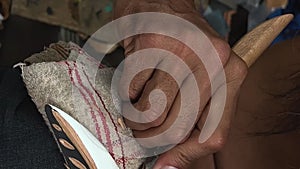 on the street a man with a beard of Indian appearance the first people of Canada locals carving a feather on a tree