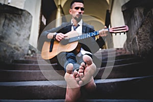 Street musician playing the guitar outdoors. Selective focus on feet. Music, art, creativity concept