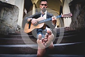 Street musician playing the guitar outdoors. Selective focus on feet. Music, art, creativity concept