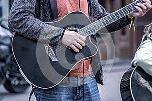 The street musician plays the black electric guitar.  Musicians raising money