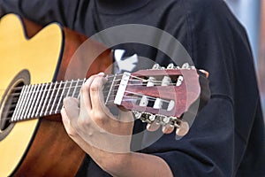 A street musician plays the guitar. Close-up of hands plucking chords. Guitar neck