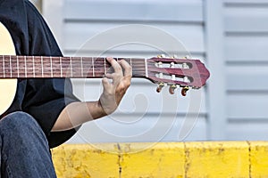 A street musician plays the guitar. Close-up of hands plucking chords. Guitar neck