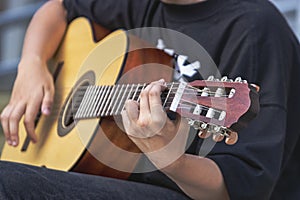 A street musician plays the guitar. Close-up of hands plucking chords. Guitar neck