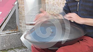The street musician plays a metal drum