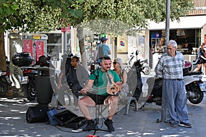 Street musician singing and playing Cretan lyra, traditional Greek music instrument.