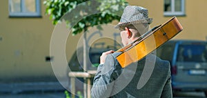 Street musician walking with a guitar on his shoulder. Music, art, creativity concept