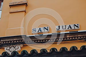 Street name sign on a building on San Juan in Seville, Spain