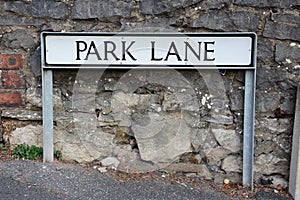 Street name sign for Park Lane mounted in front of a stone wall