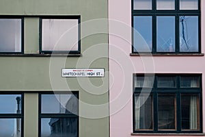 Street name sign on pastel coloured buildings on Whitechapel High Street, London, UK