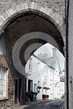 Street of old picturesque houses through the arch of the medieval gatehouse in the village of cartmel in cumbria