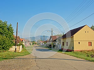 Street in the old Romanian village Aurel Vlaicu with transylvanian mountains in the background